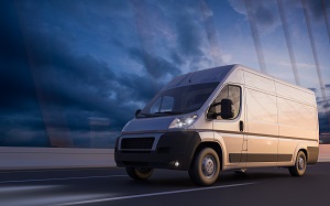 white commercial van driving down the road at sunset